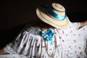 Un primer plano de un vestido tradicional de pollera adornado con un sombrero de paja y una vibrante cinta azul, que muestra la elegancia cultural.